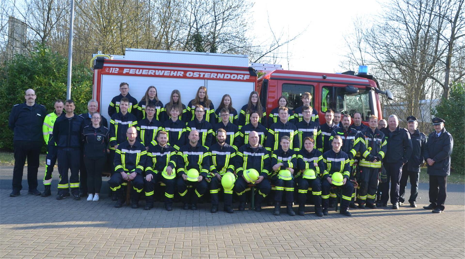 Gruppenfoto von Feuerwehrleuten in Einsatzkleidung vor einem roten Löschfahrzeug der Feuerwehr Osterndorf