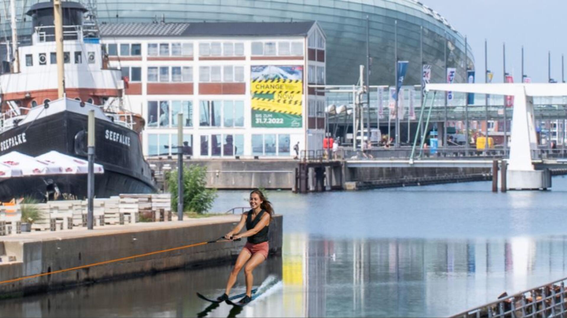 Fotomontage: Eine Frau fährt im Alten Hafen in Bremerhaven Wasserski.
