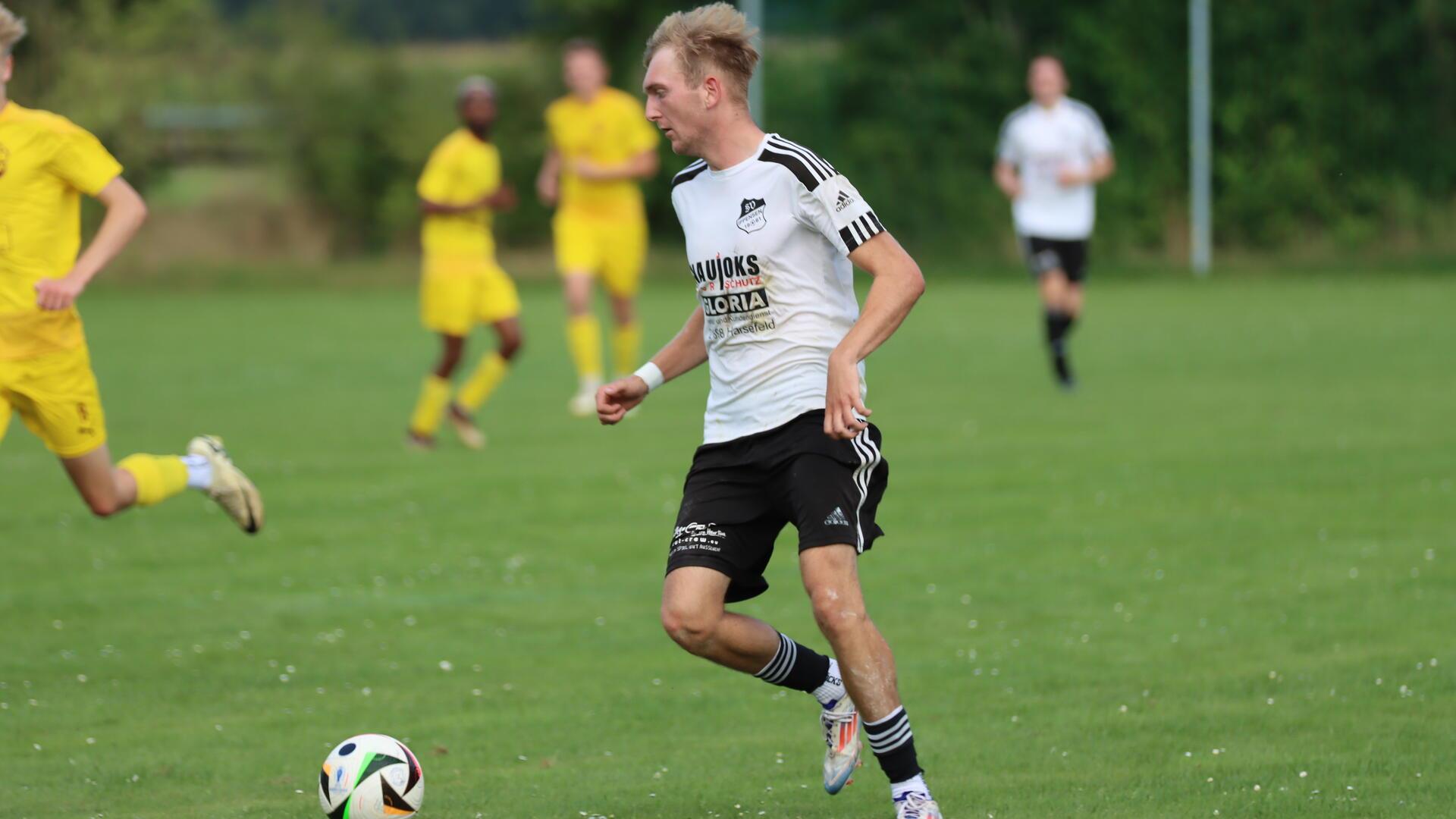 Ein Mann läuft mit einem Ball am Fuß.