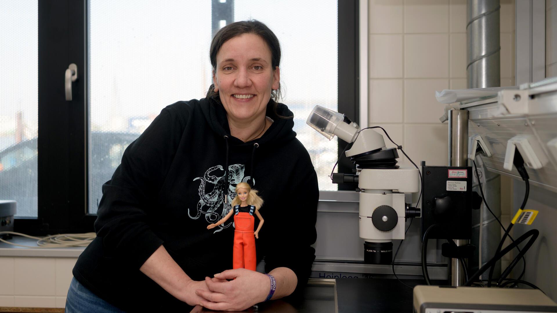 Eine Frau steht mit einer kleinen Puppe in einem Labor. Alexandra Poell mit ihrem Fischereiforschungspüppchen Sandy.