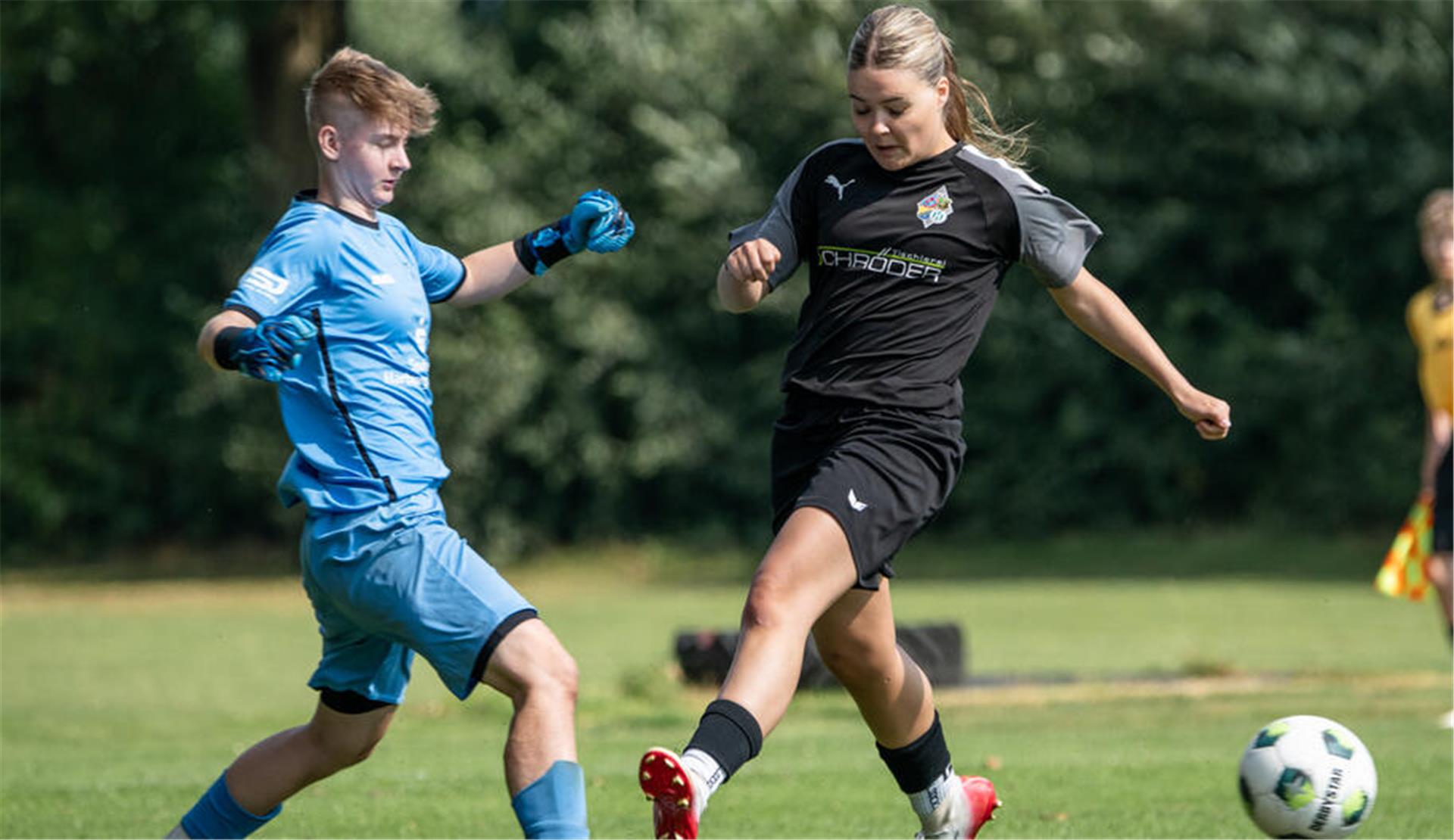 Ein Mädchen im Fußballtrikot und mit Fußballschuhen erläuft sich einen Ball.