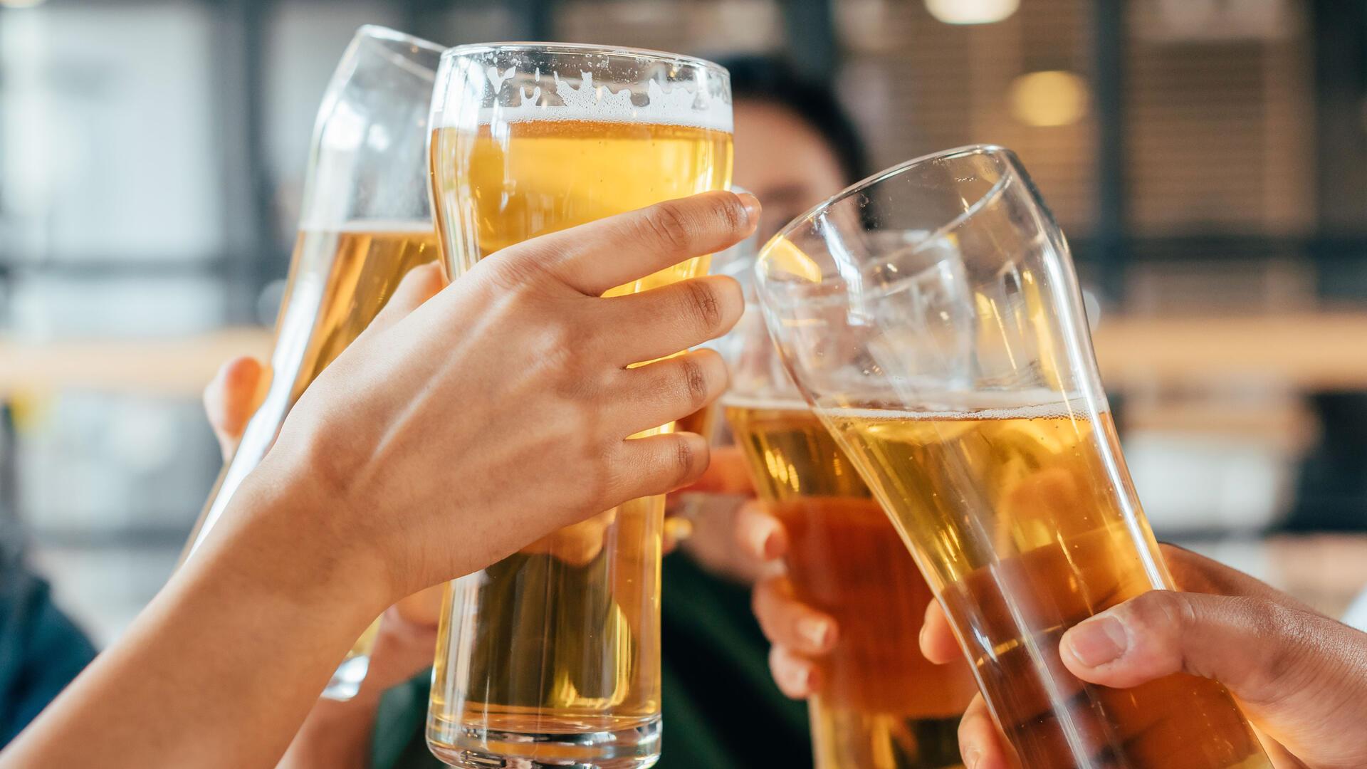 Vier Hände halten Biergläser und stoßen an. Alkohol gehört zu so gut wie jedem sozialen Event in Deutschland dazu. Aber wer trinkt am liebsten welches Getränk? Und wann nimmt der Konsum überhand?