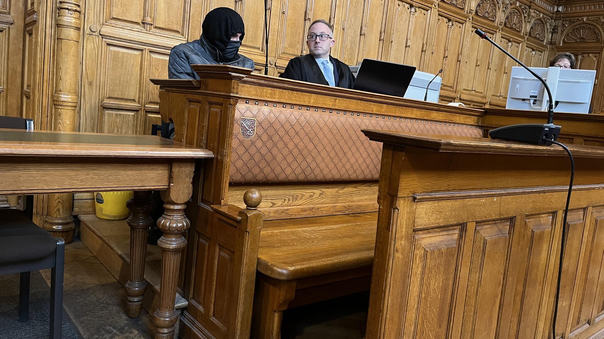 Angeklagter sitzt mit Maske neben seinem Verteidiger. 