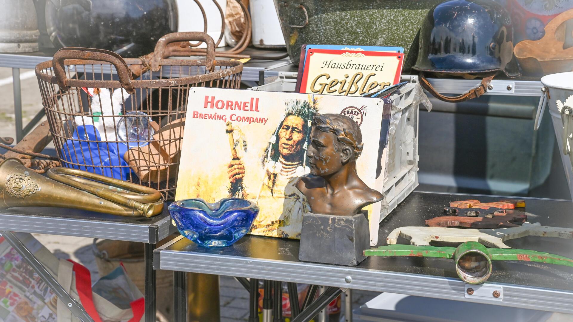 Verschiedene Waren stehen auf einem Flohmarkttisch und werden zum Verkauf angeboten. Der Flomaxx-Flohmarkt lockt viele Besucher auf den Ikea-Parkplatz am Bohmsiel.