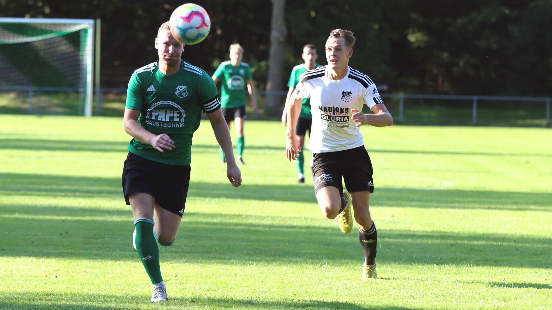 Zwei Männer laufen hinter einem Ball her.