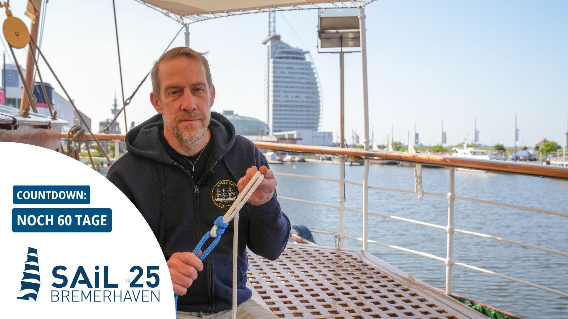 Ein Mann sitzt in Bremerhaven an Bord der „Schulschiff Deutschland“ und erklärt den Schotstek – einen Seemannsknoten.