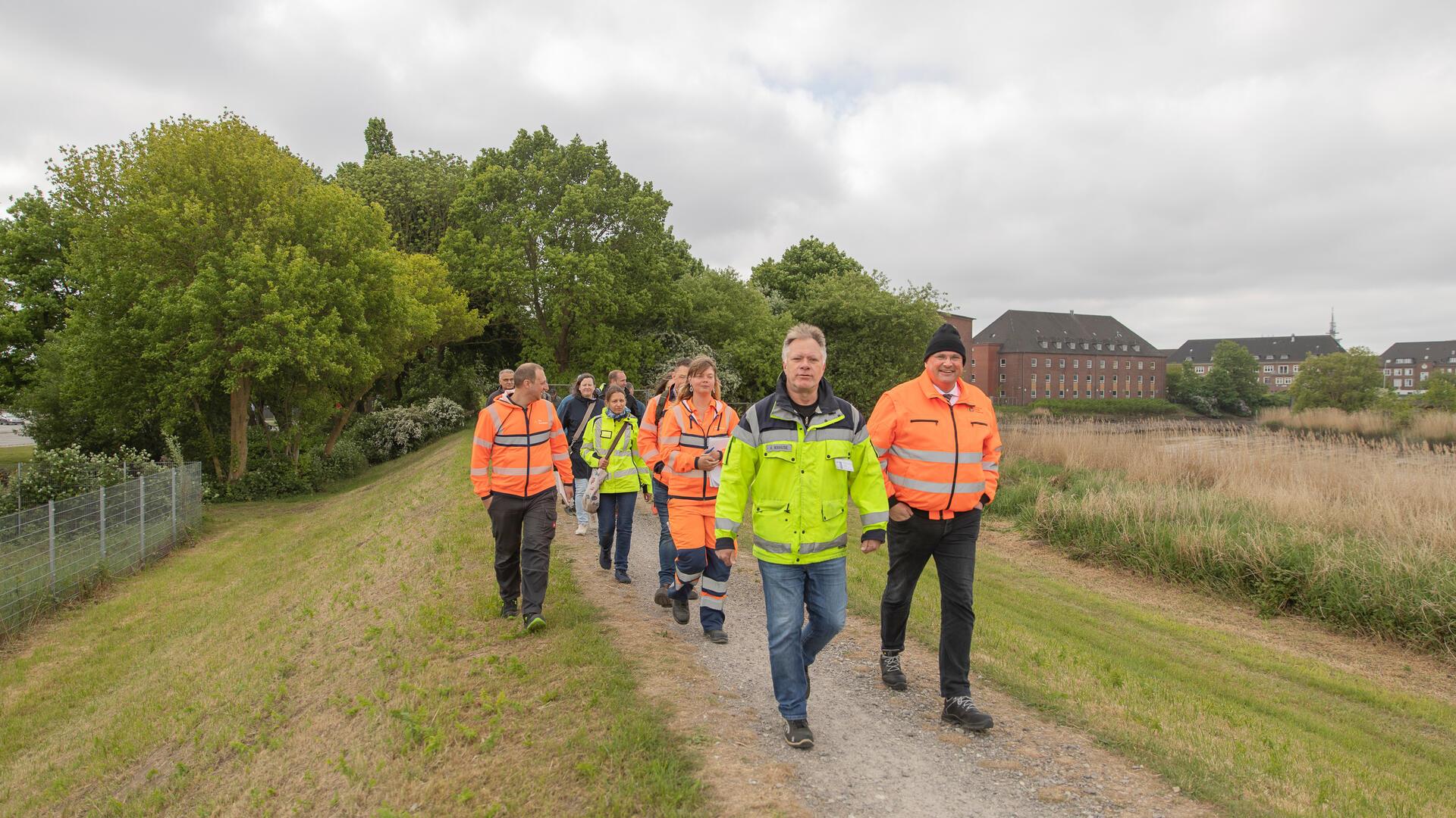 Menschen laufen auf dem Geeste-Deich. Andreas Krause (links) und EBB-Vorstand Markus Kamps (rechts) führen die Gruppe bei der Deichschau in Bremerhaven an.