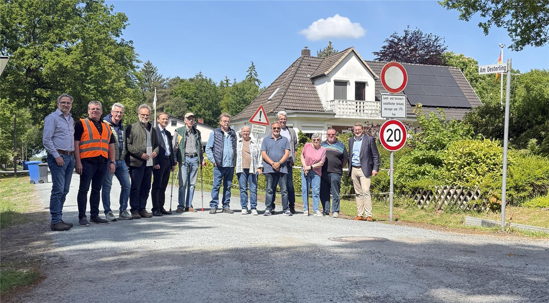 Eine Gruppe von Personen, die auf einer Straße steht. Die Straße "Am Oesterling" in Geestenseth hat jetzt eine Tränkdeckschicht.