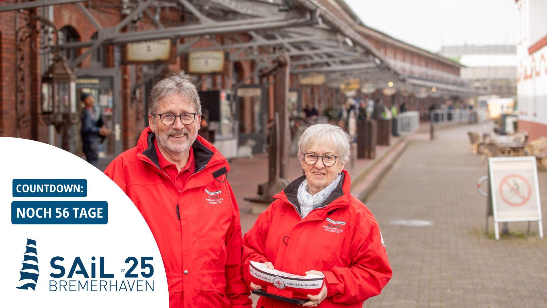 Zwei Personen in roten Jacken halten ein Sammelschiff der Seenotretter.