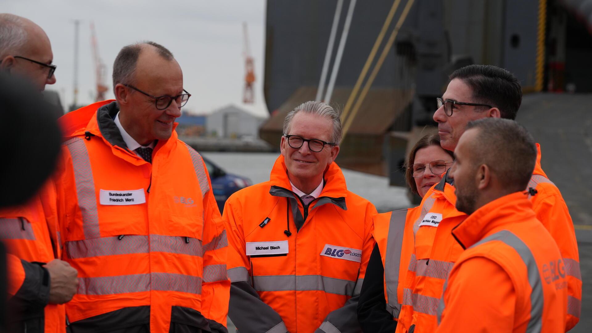 Bundeskanzler Friedrich Merz spricht im Bremerhavener Hafen mit einem Mitarbeiter.
