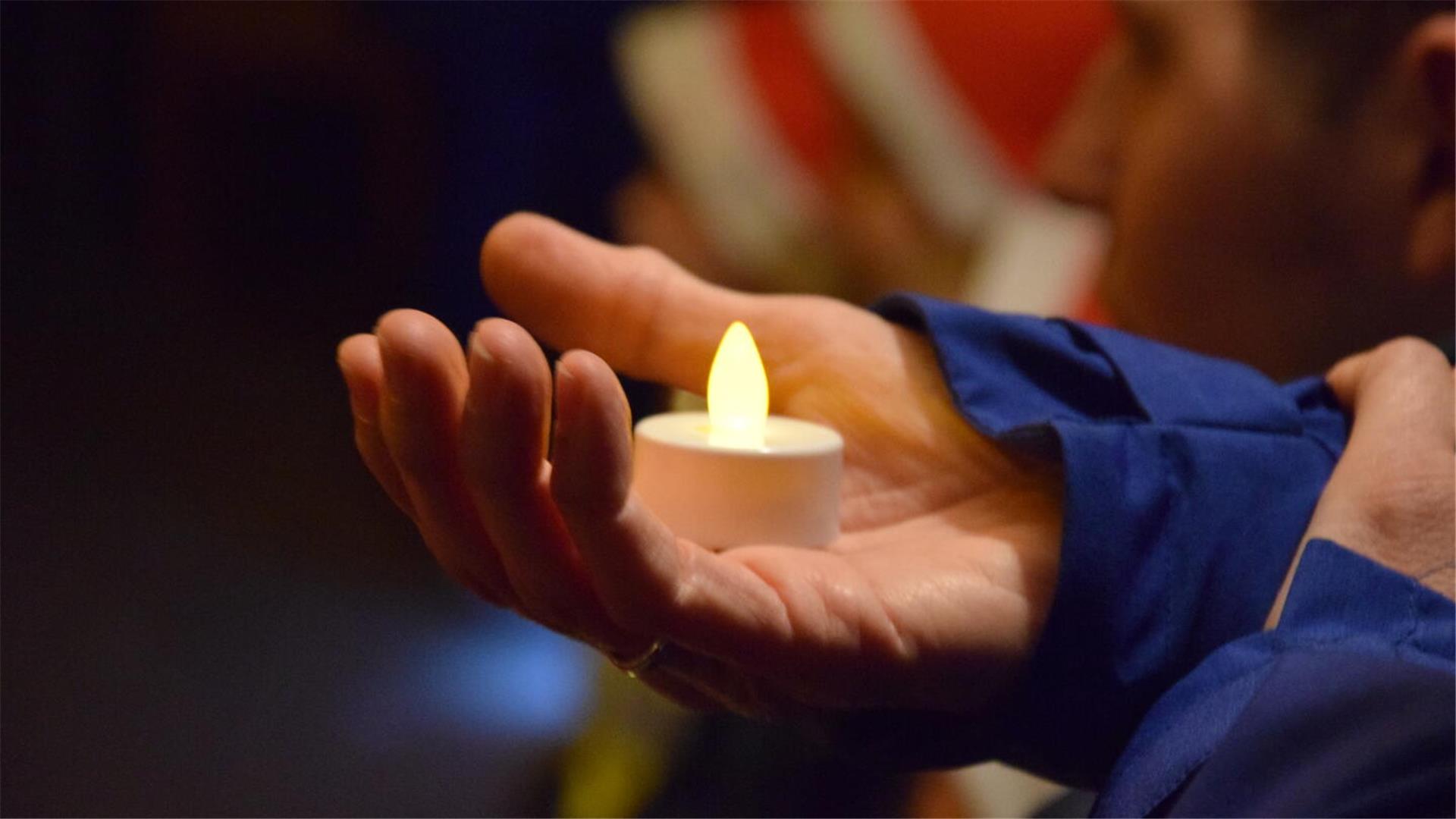 Hand hält ein batteriebetriebenes Teelicht