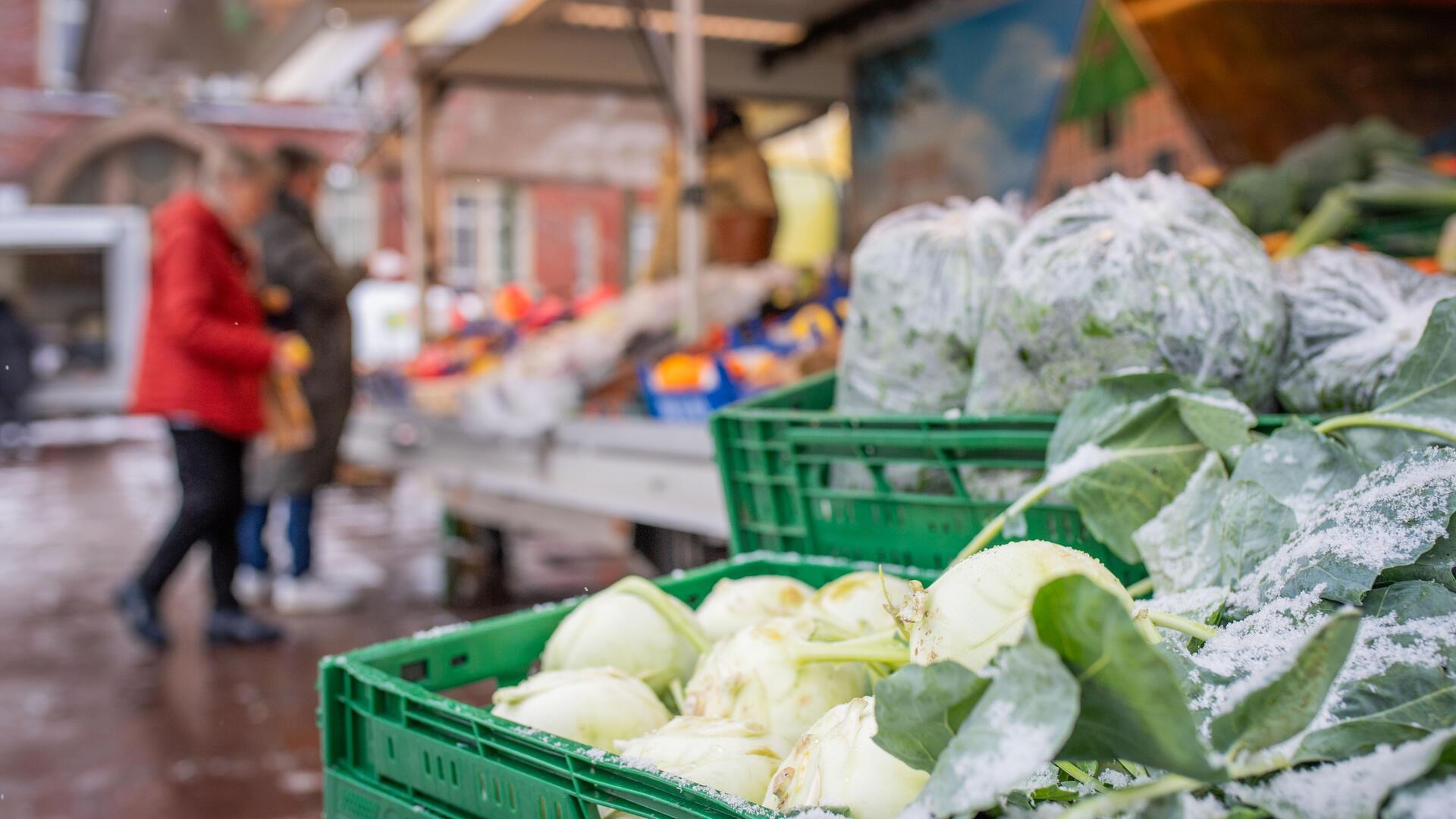 Gemüse ist im rechten Vordergrund scharf zu sehen. Im Hintergrund unscharf: Menschen beim Einkaufen. Auf dem Wochenmarktplatz in Lehe präsentieren inhabergeführte Läden ihre Angebote beim „Heimat shoppen“. Parallel läuft der Wochenmarkt.
