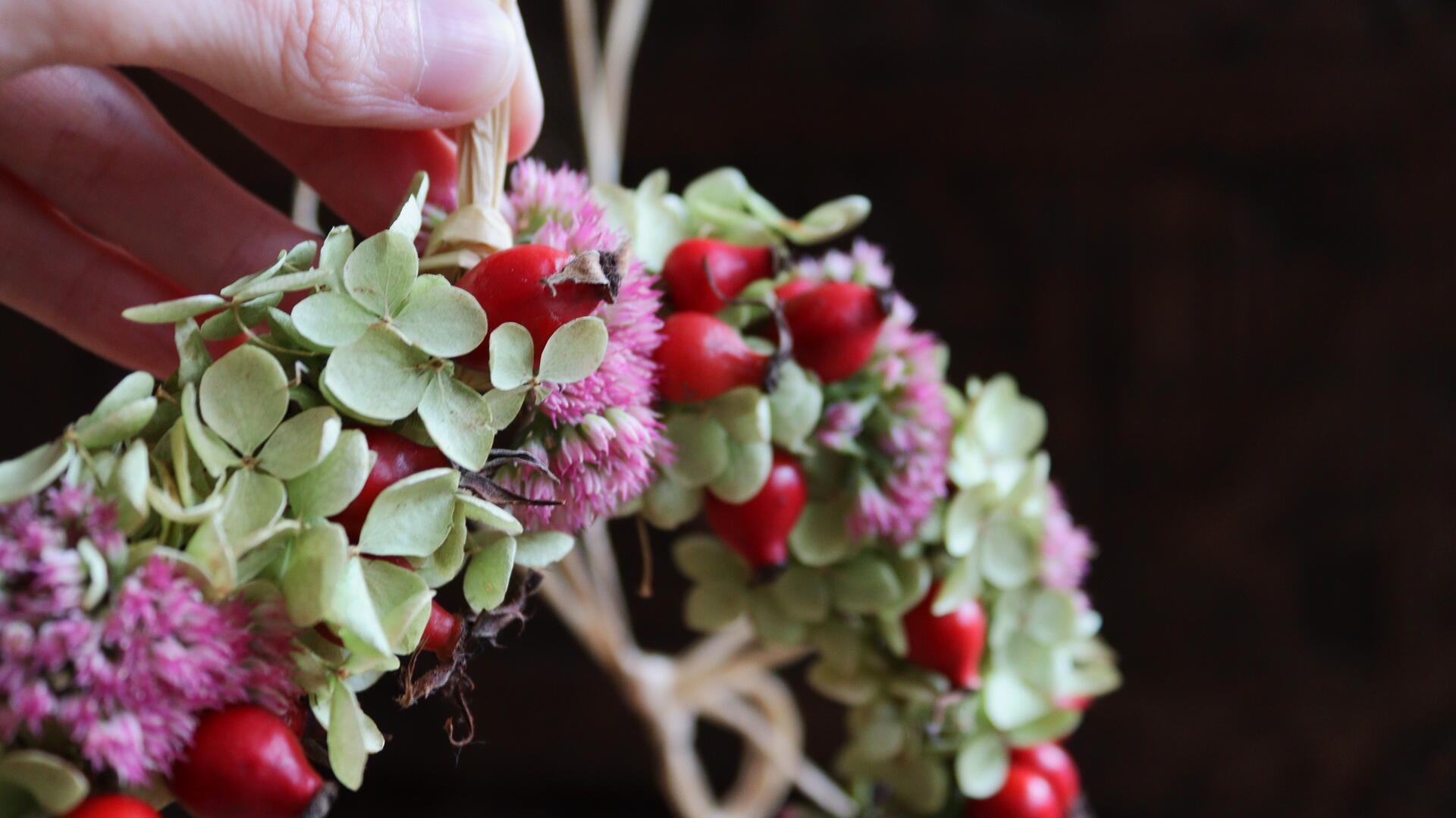 Hand hält Blumenkranz