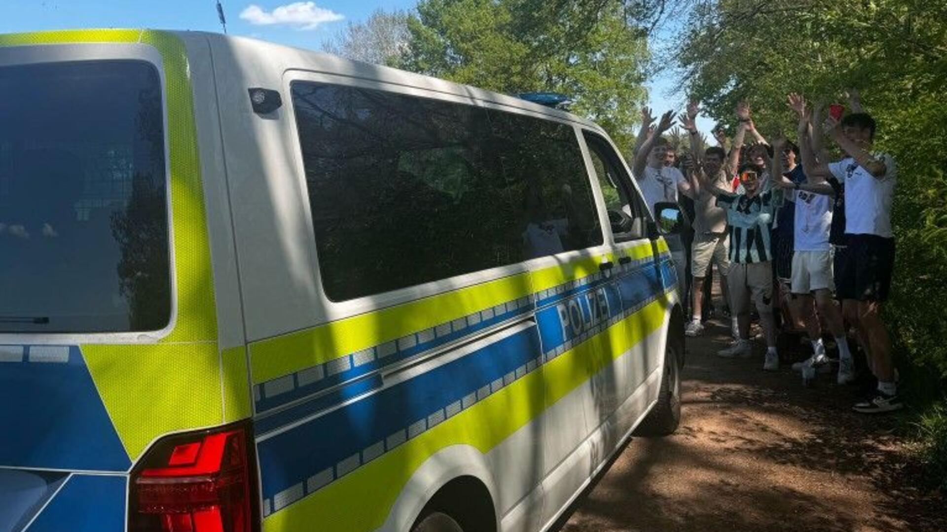 Ein Polizeibus und davor jubelnde junge Menschen.