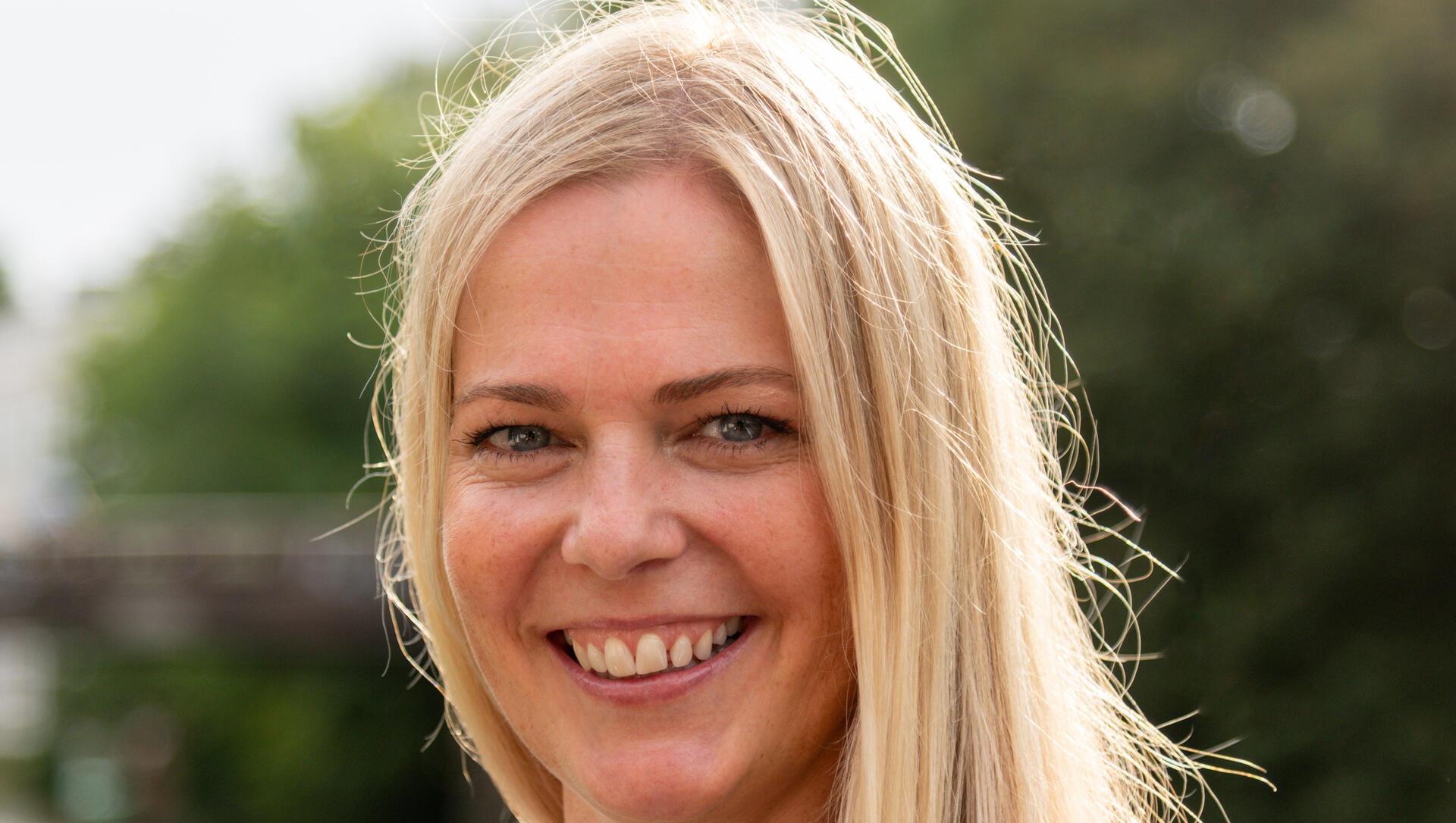 Eine lächelnde Frau mit langen blonden Haaren.