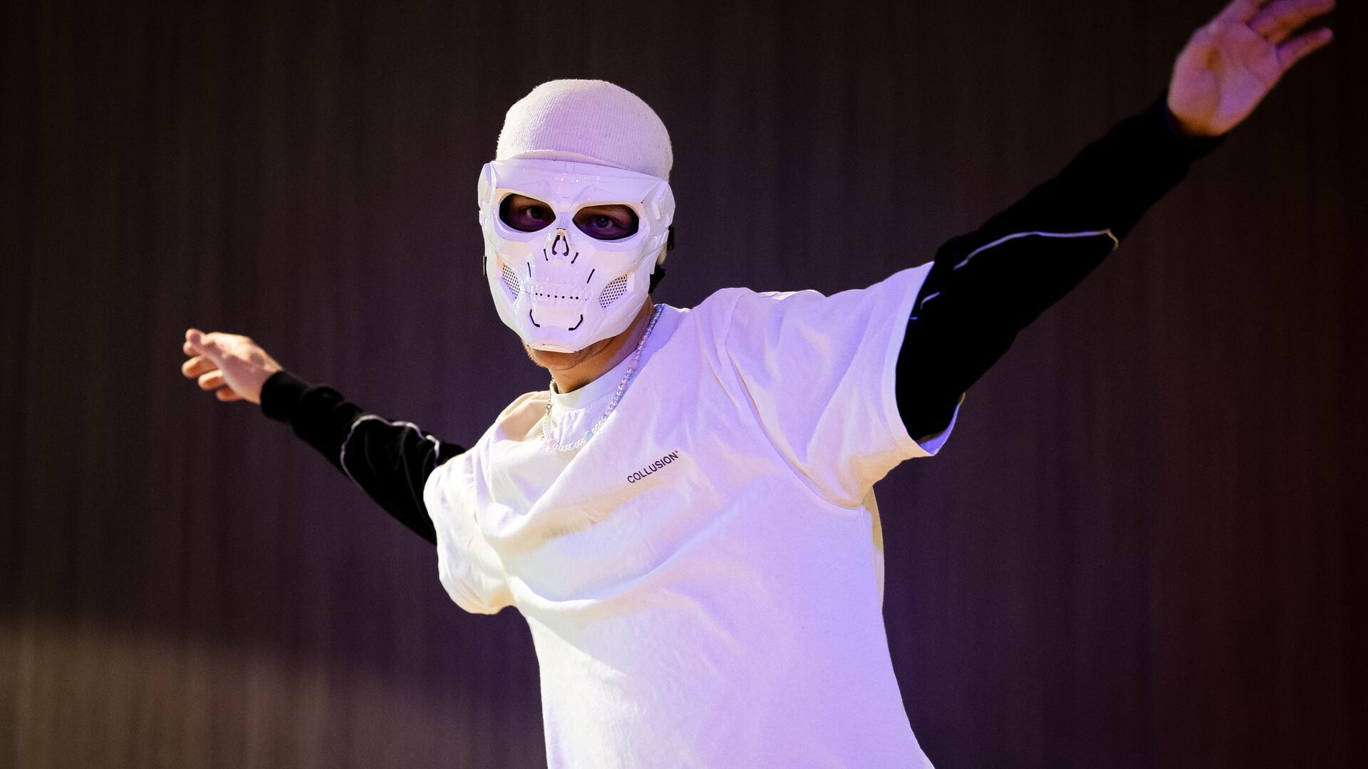 Ein Mann mit Maske tanzt in einem Studio.