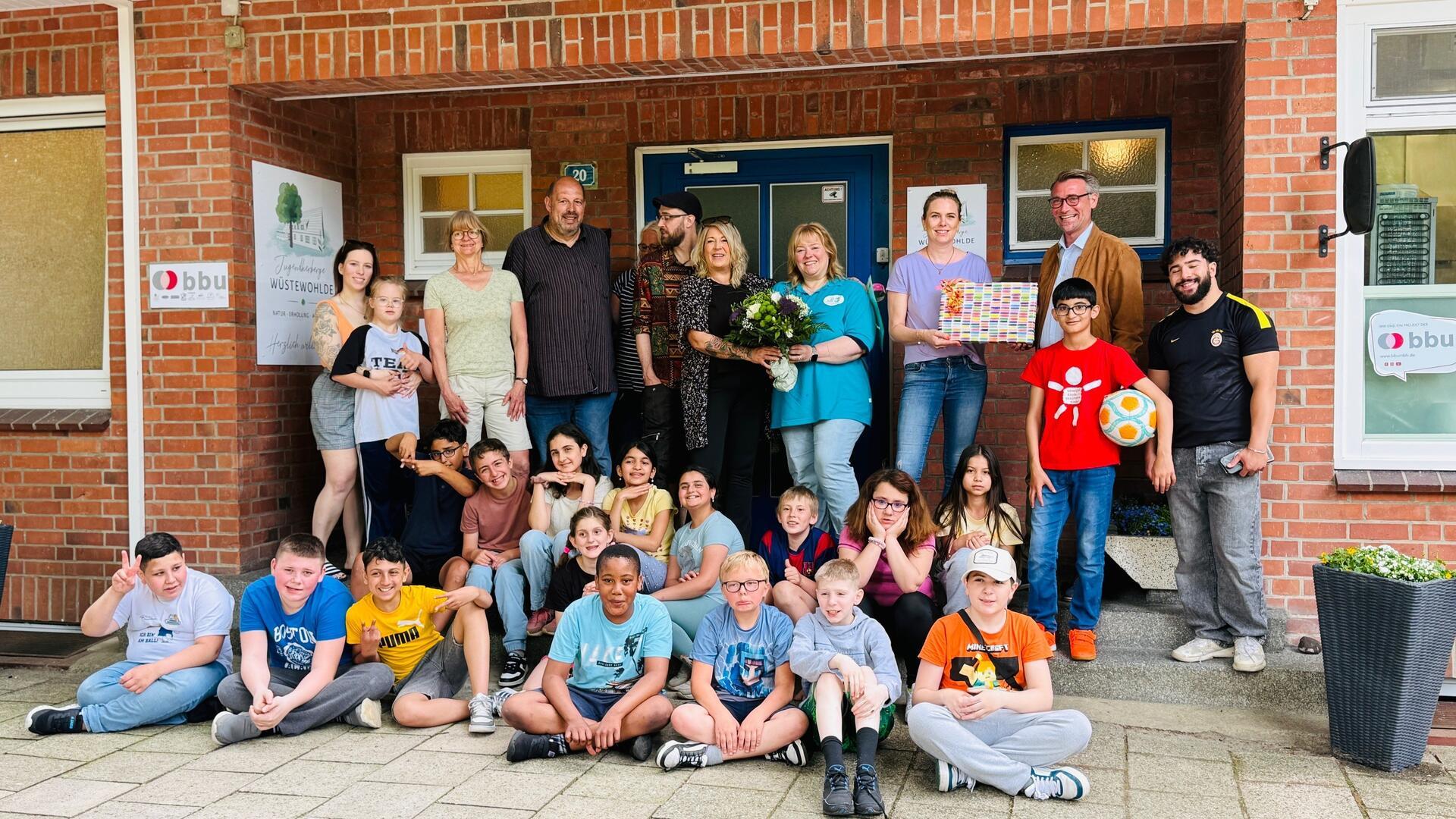 Gruppenfoto mit einer Schulklasse und Erwachsenen. Geschäftsführer der BBU Gerrit Michaelis und die Leiterin der JGH Wüstewohlde Petra Schulz begrüßen die Klassenlehrerin Annika Jacobsen und Steffi Roß-Heitmann in der Jugendherberge Wüstewohlde.