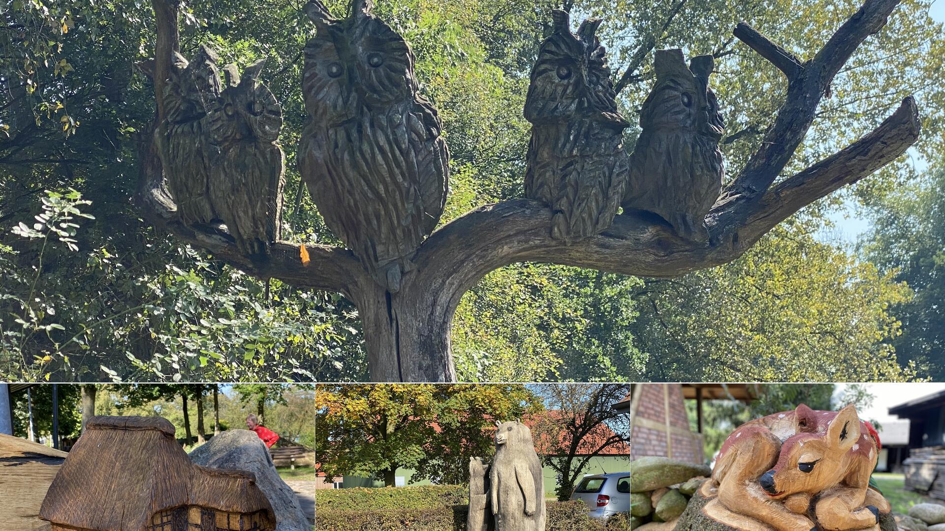 Mehrere geschnitzte Eulen in einem abgestorbenen Baum, ein Rehkitz, ein Bär und eine Moorkate - ebenfalls aus Holz.