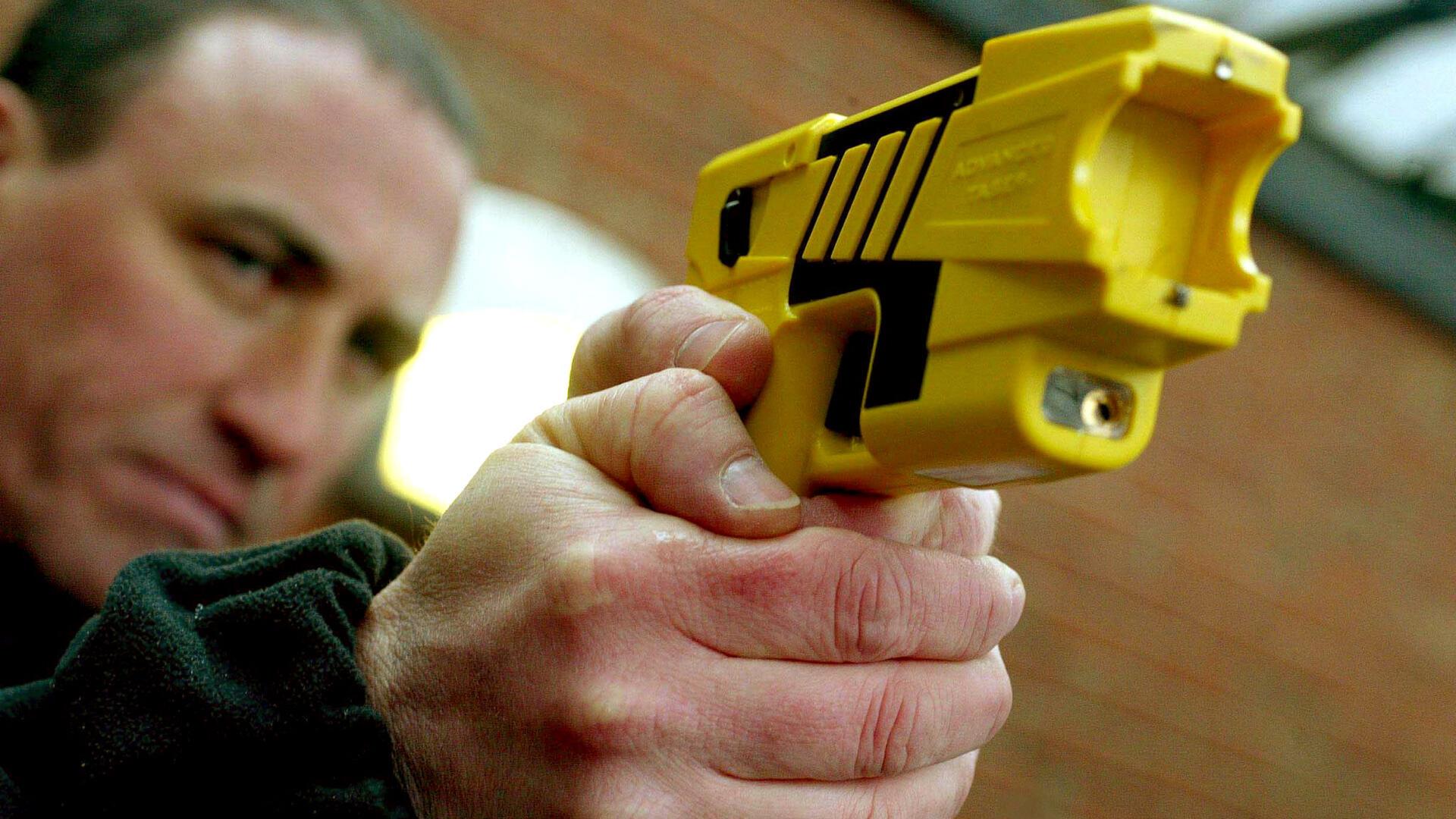 Mann zielt mit einem Taser.