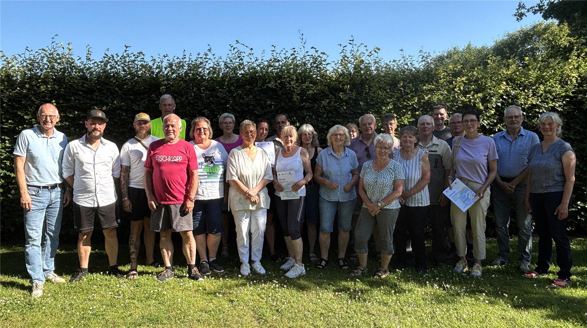 Gruppenbild der Teilnehmenden und Ausgezeichneten des Loxstedter Stadtradelns 2025 bei der Siegerehrung, aufgenommen im Freien vor einer grünen Hecke.