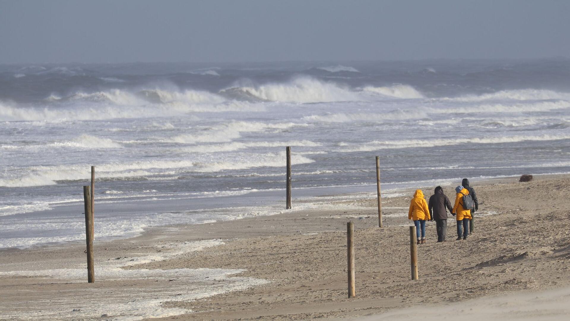 Orkanböen bis 130 km/h: Es wird stürmisch in Bremerhaven, Cuxland und Wesermarsch Bei stürmischem Wetter und Wellen gehen Spaziergänger am Strand der Insel Norderney entlang.