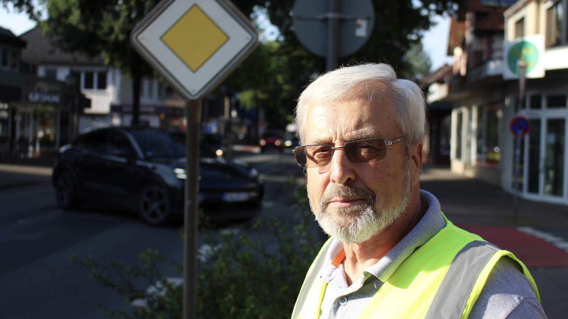 Mann mit Warnweste vor Verkehrsschild stehend
