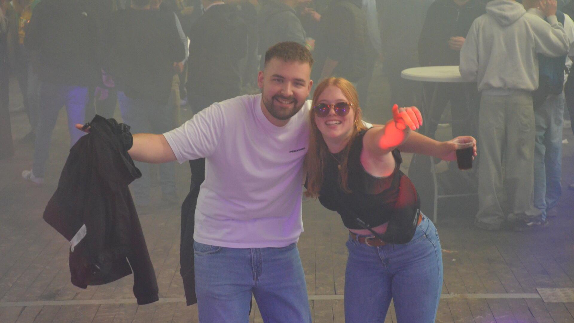 Ein junger Mann und eine junge Frau lächeln in die Kamera.