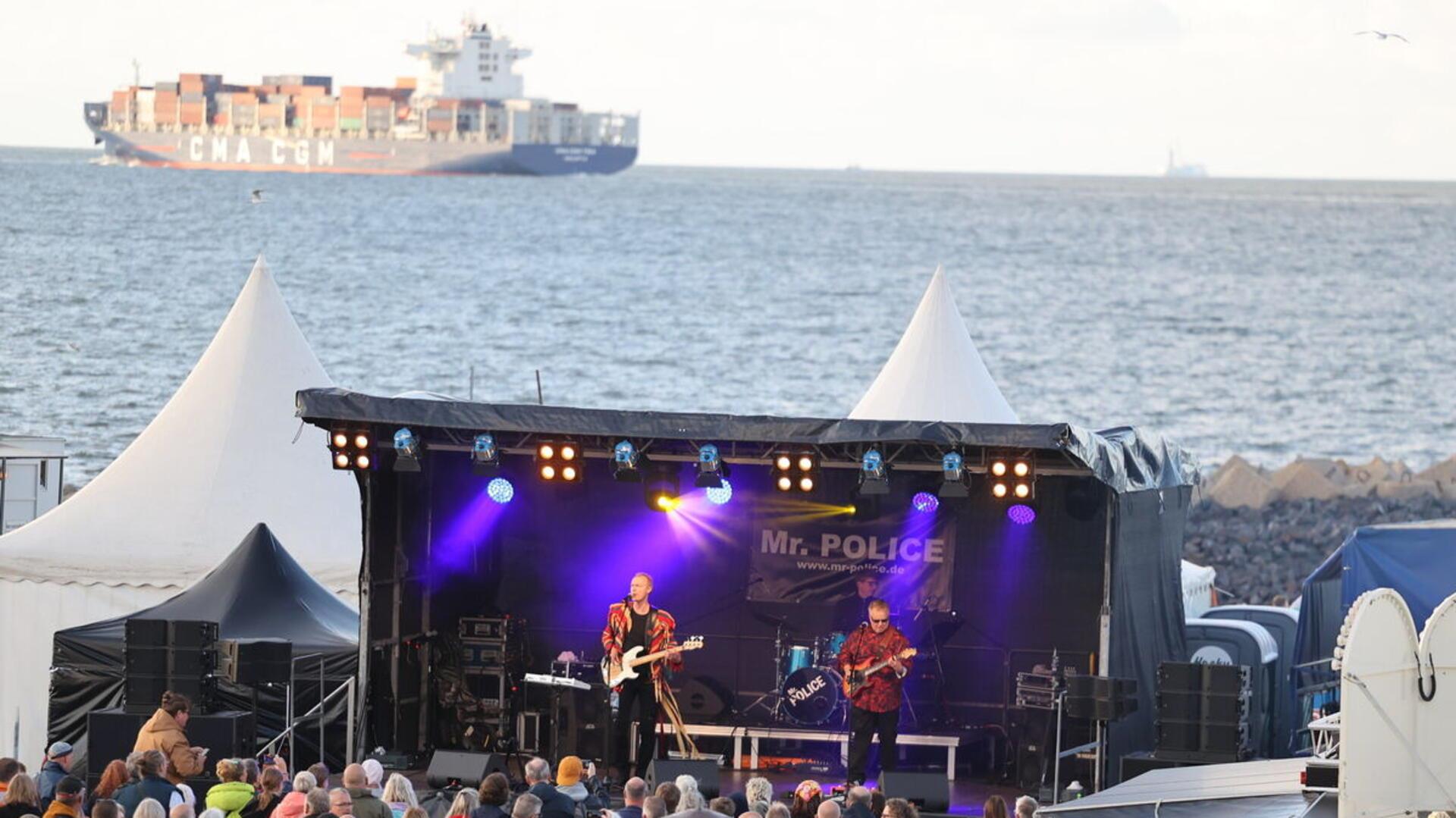 Besucher genießen den Sound von Mr. Police vor der malerischen Kulisse der Elbmündung in Cuxhaven.