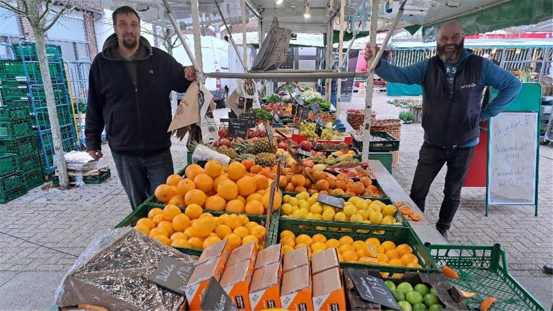 Zwei Männer an ihrem Stand auf dem Wochenmarkt.