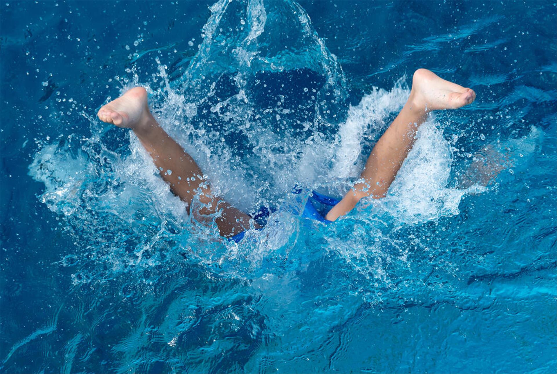  Ein Junge springt ins Wasser. 