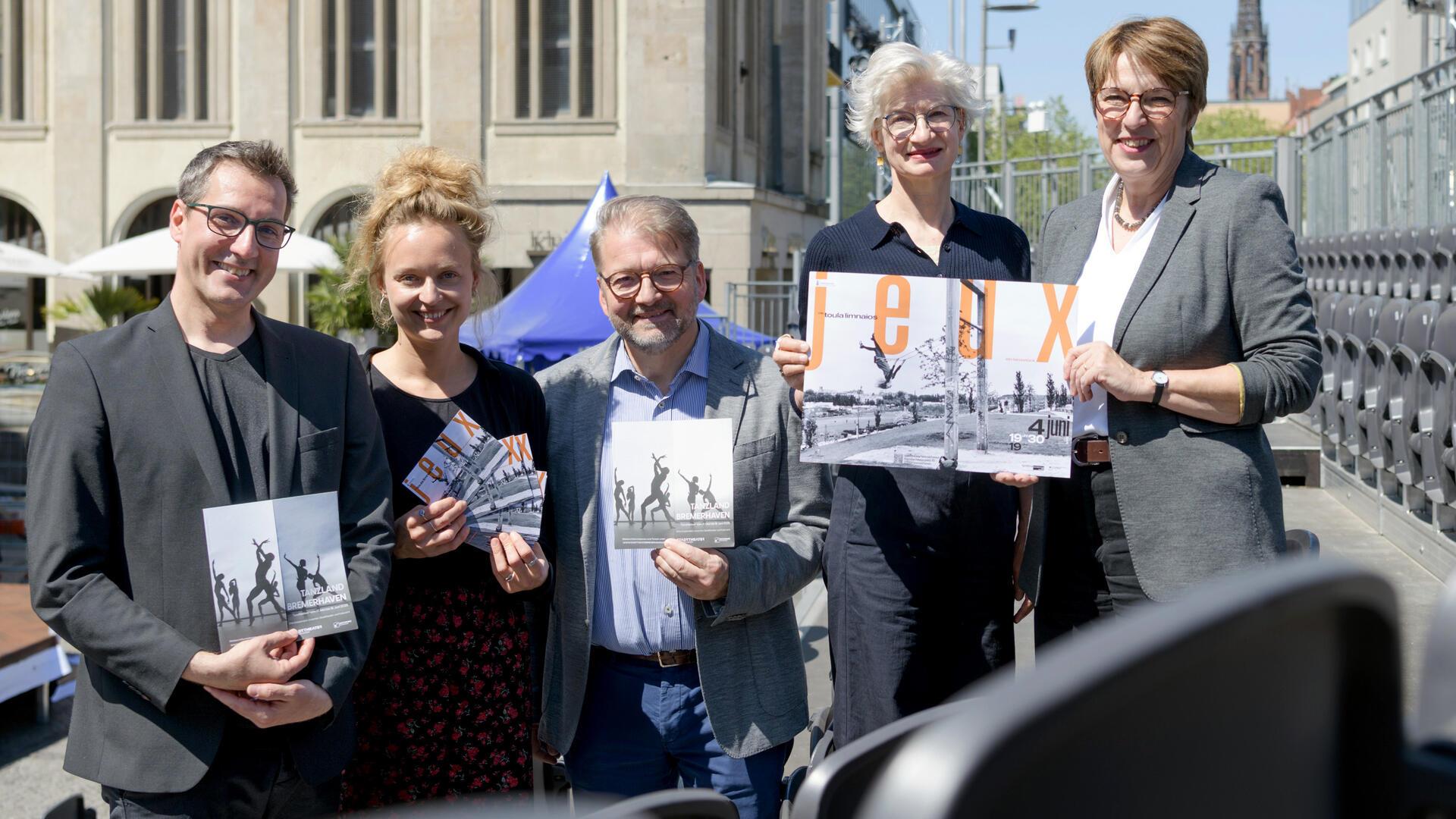 Fünf Personen, zwei Männer und drei Frauen, halten Flyer und ein Plakat in die Kamera.