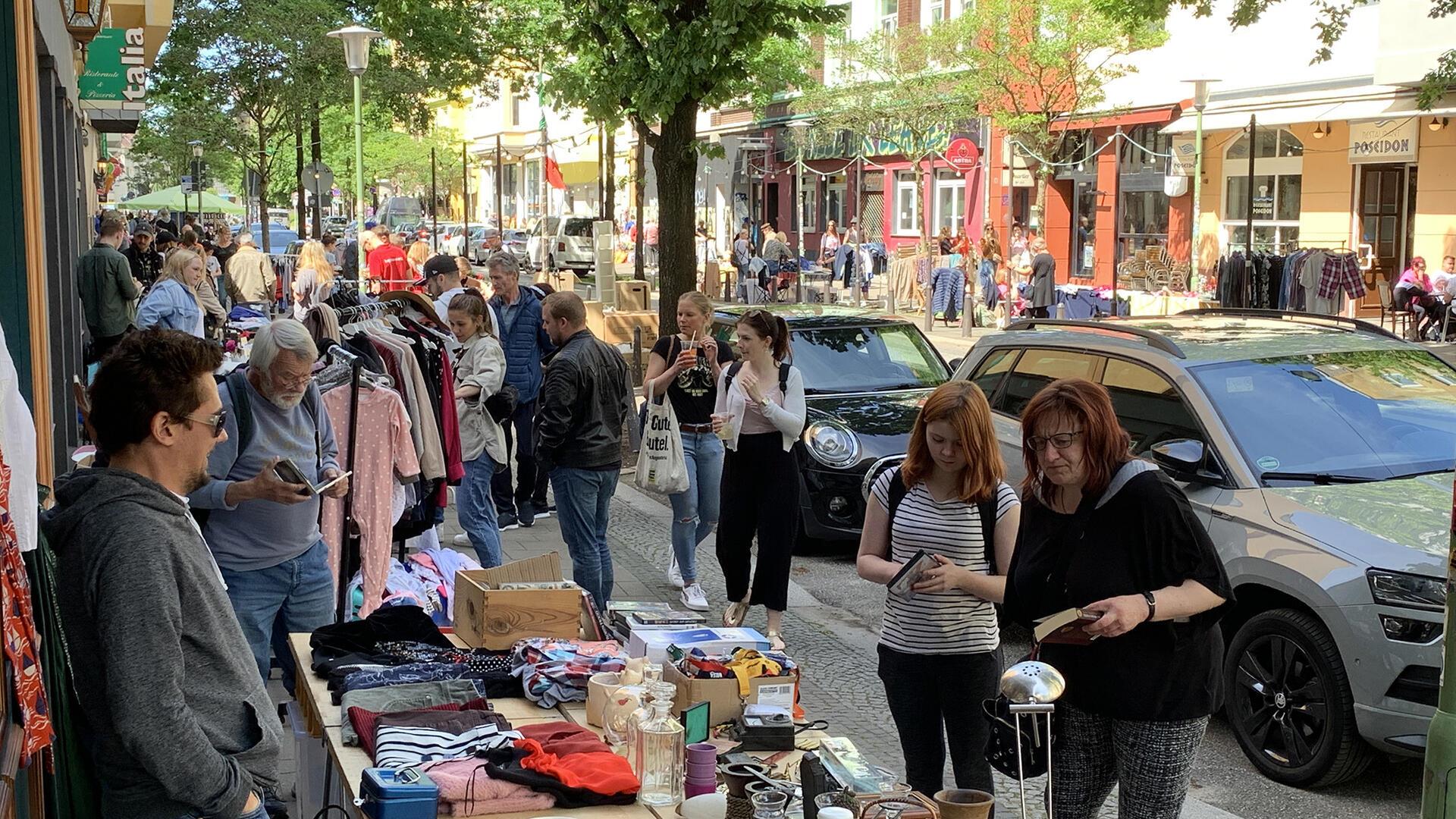 Besucherinnen und Besucher stöbern an mehreren Flohmarktständen in der Straße "Alte Bürger"