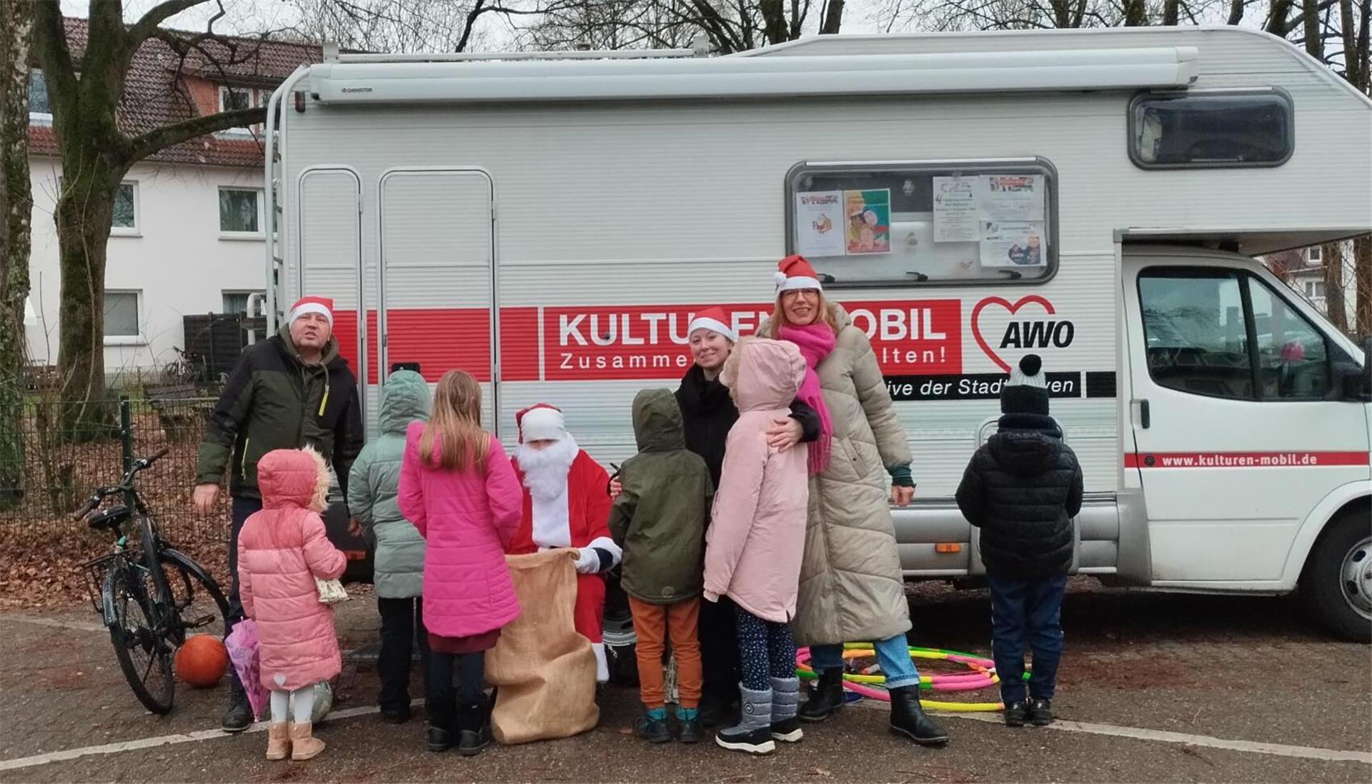 Einige Kinder versammeln sich um den Nikolaus vor dem Kulturen-Mobil.