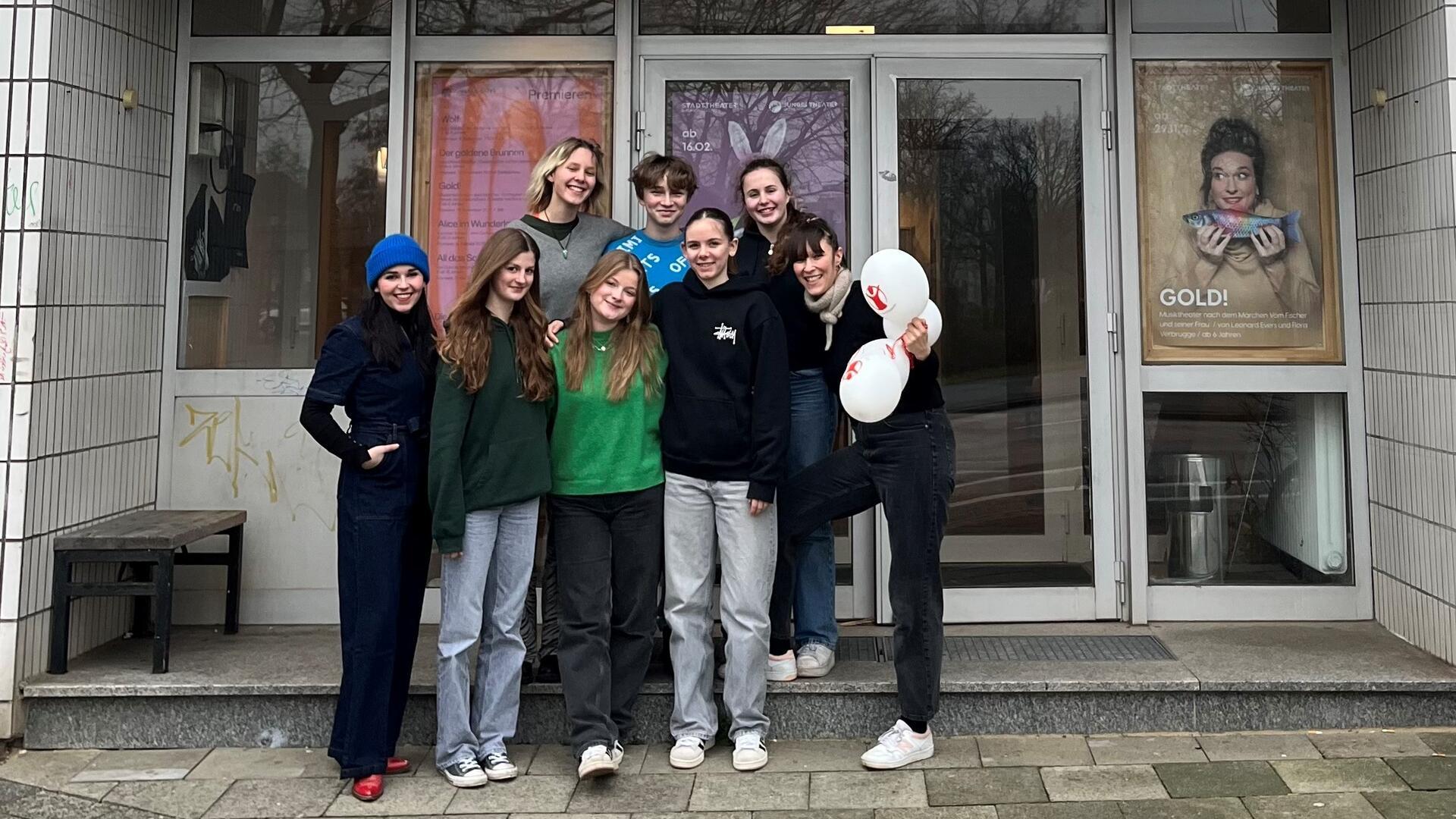 Jugendliche des Theaterlabor+ stehen vor dem Gebäude des Jungen Theaters Bremerhaven. 