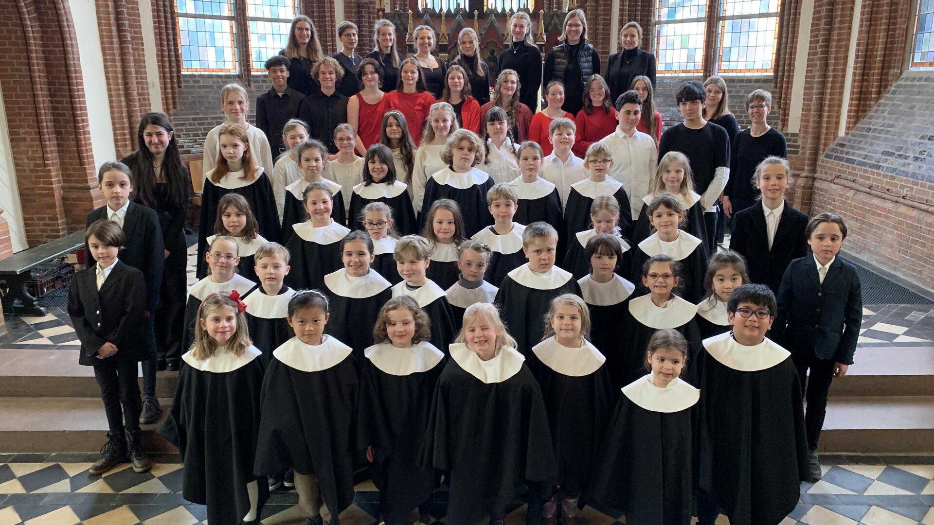 Kinder und Jugendliche haben sich in einer Kirche aufgestellt.