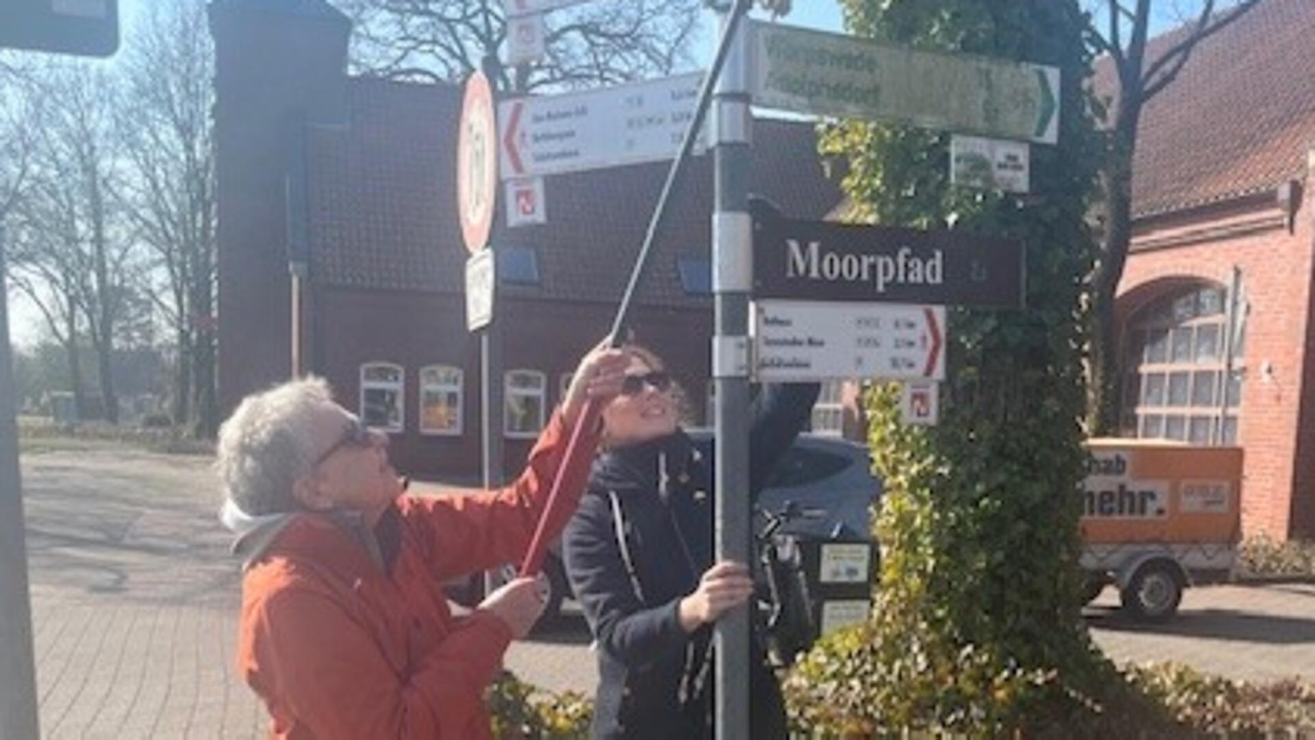Zwei Frauen reinigen ein Radwegschild in Tarmstedt. 