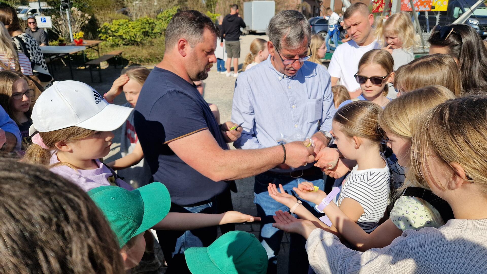 Zwei Männer verteilen Freifahrtchips an Kinder.
