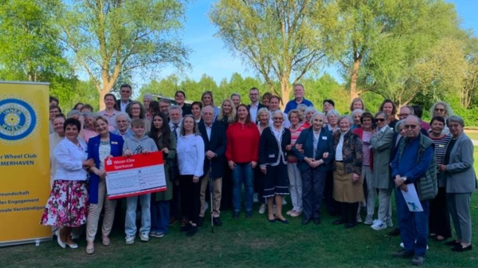 Gruppenfoto mit vielen Menschen und einem Spendecheck in Höhe von 20.000 Euro. Der Inner Wheel Club Bremerhaven hat durch eine Spendengala 20.000 Euro gesammelt.