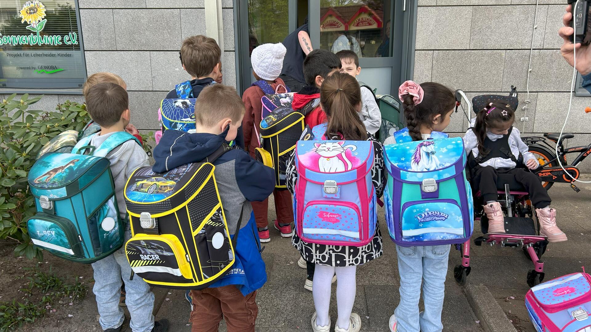 Kinder präsentieren ihre neuen Schulranzen