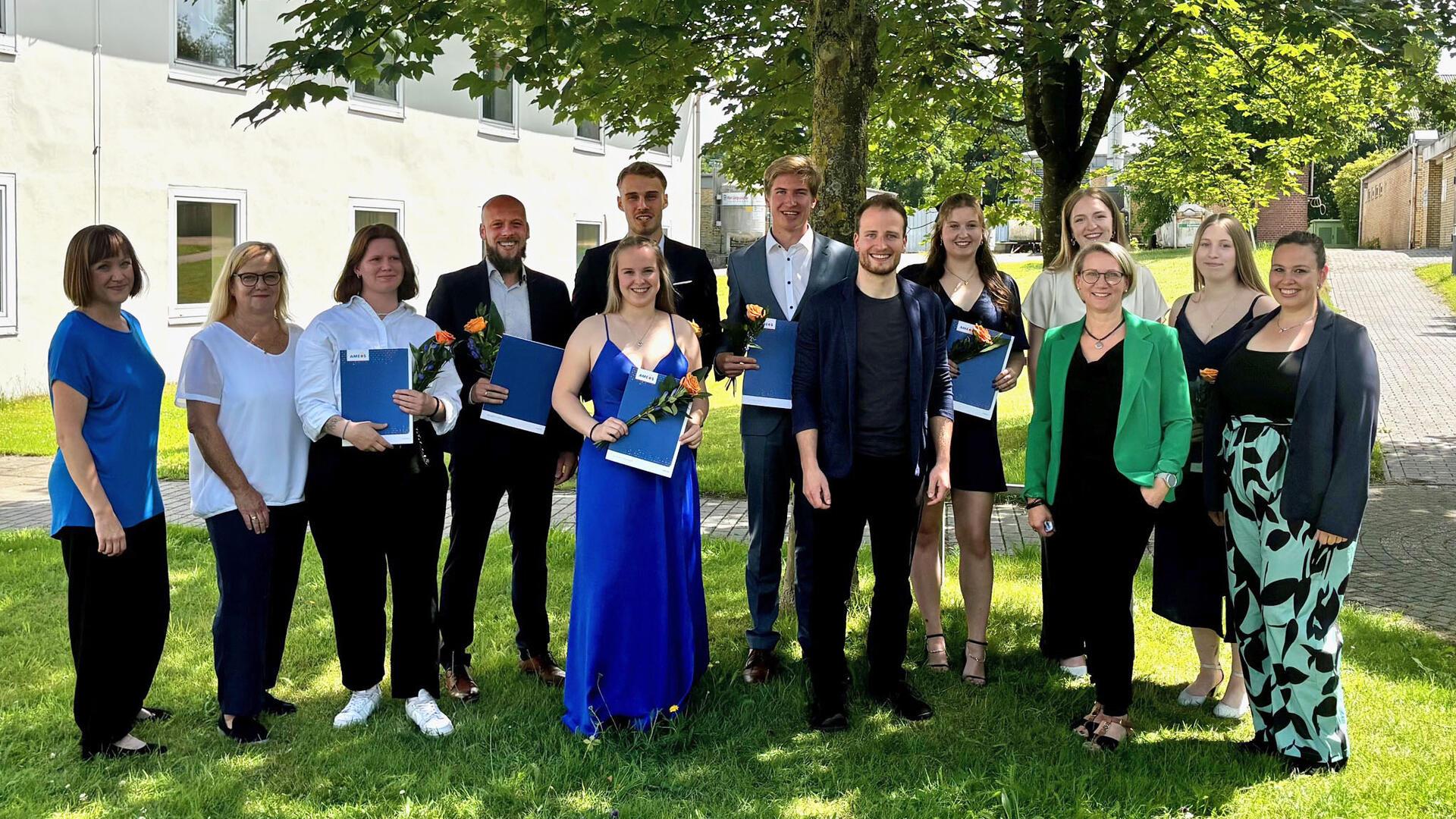 Männer und Frauen haben sich zum Gruppenfoto unter einem Baum aufgestellt
