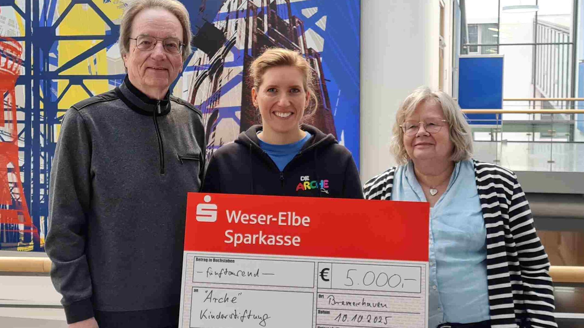Ein Mann und zwei Frauen mit einem Riesenscheck