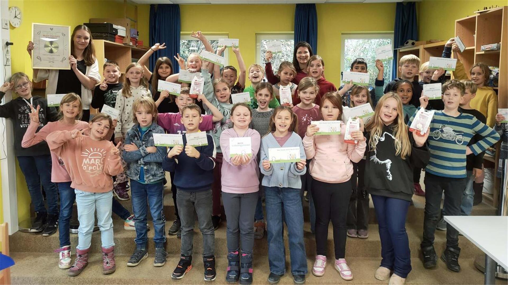 Zwei erwachsene Frau und eine Gruppe Kinder in einem Raum.