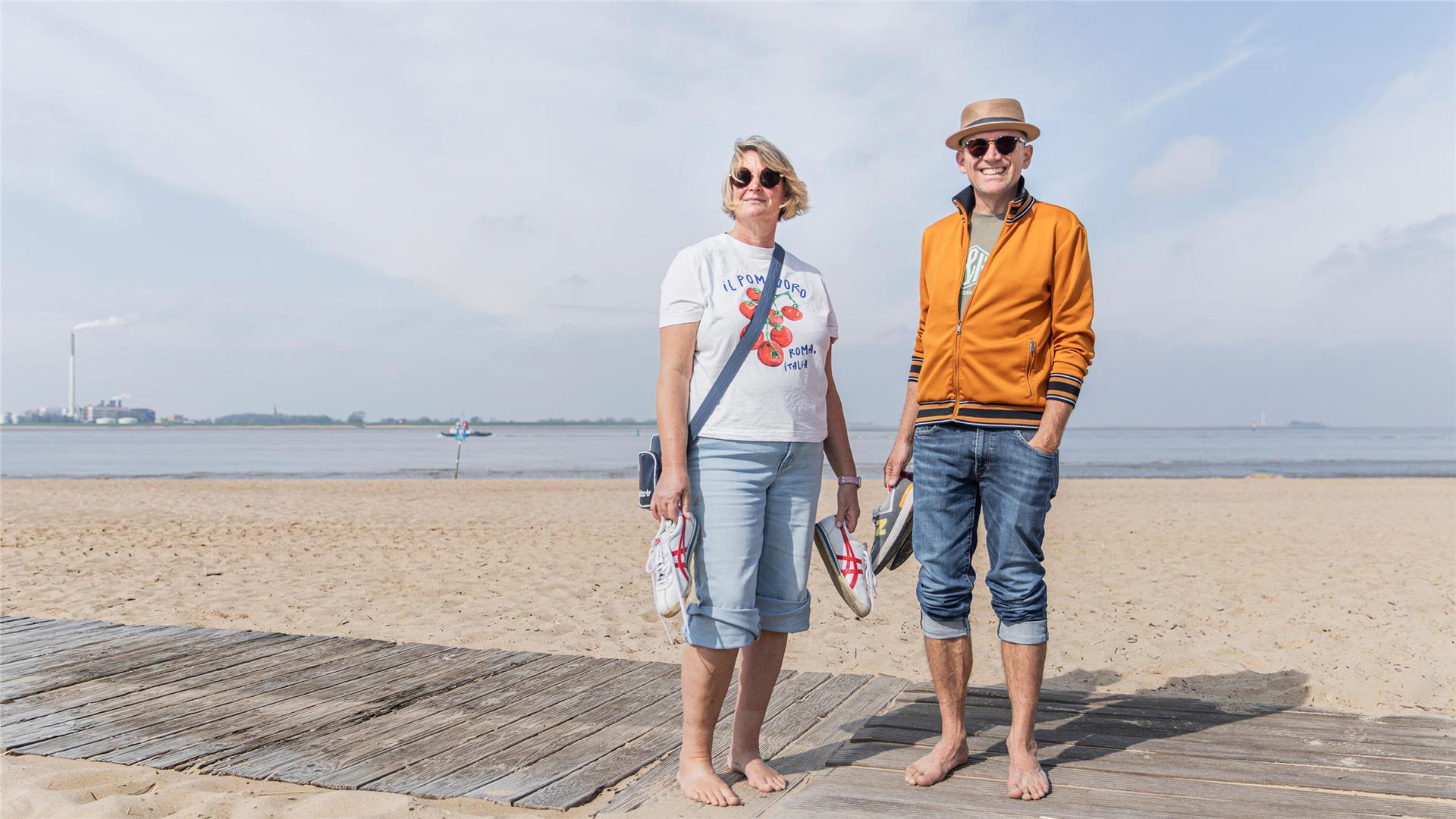 Ein Paar barfuß am Strand.