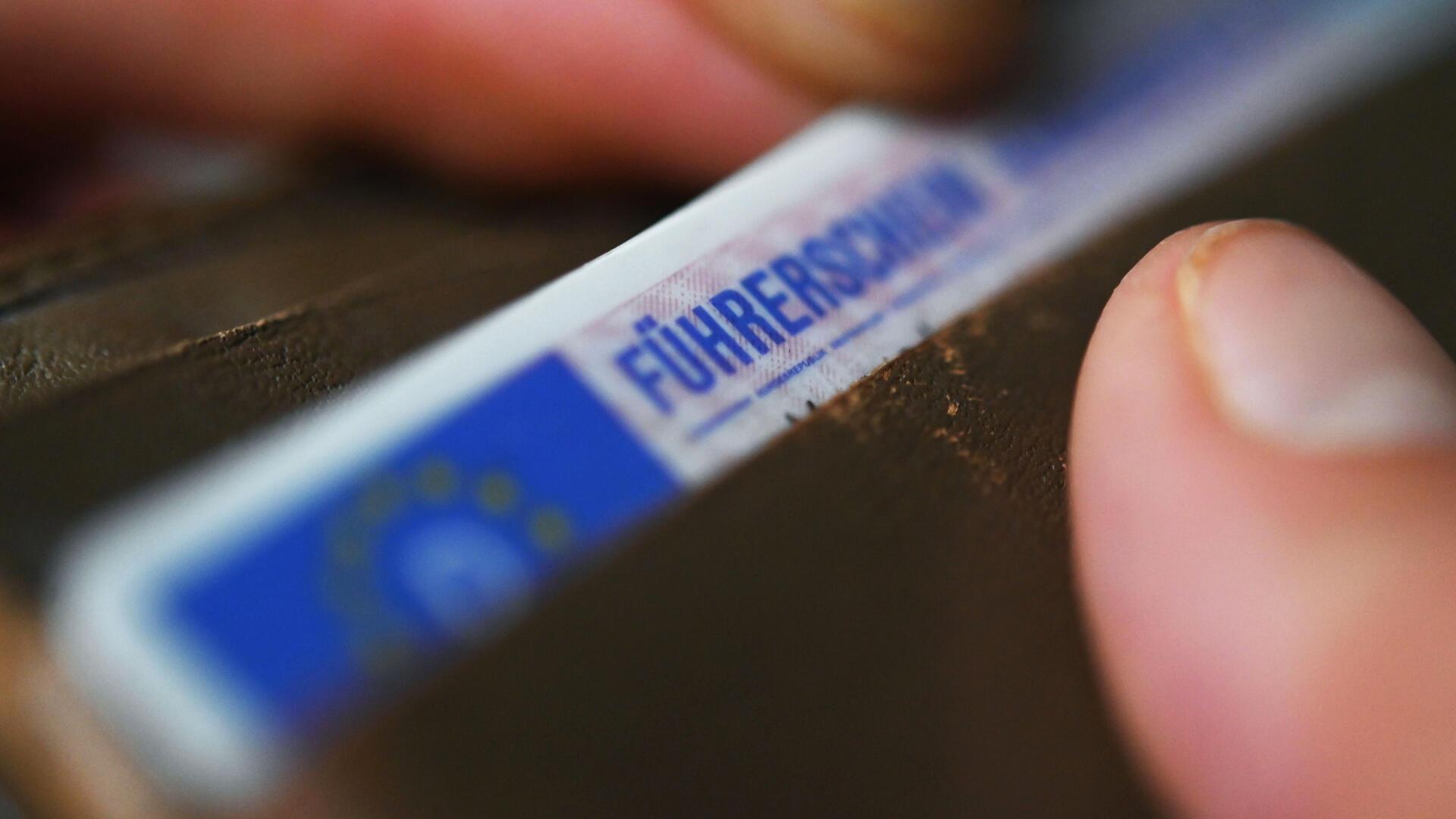 Eine Frau nimmt einen Führerschein aus ihrem Geldbeutel. 
