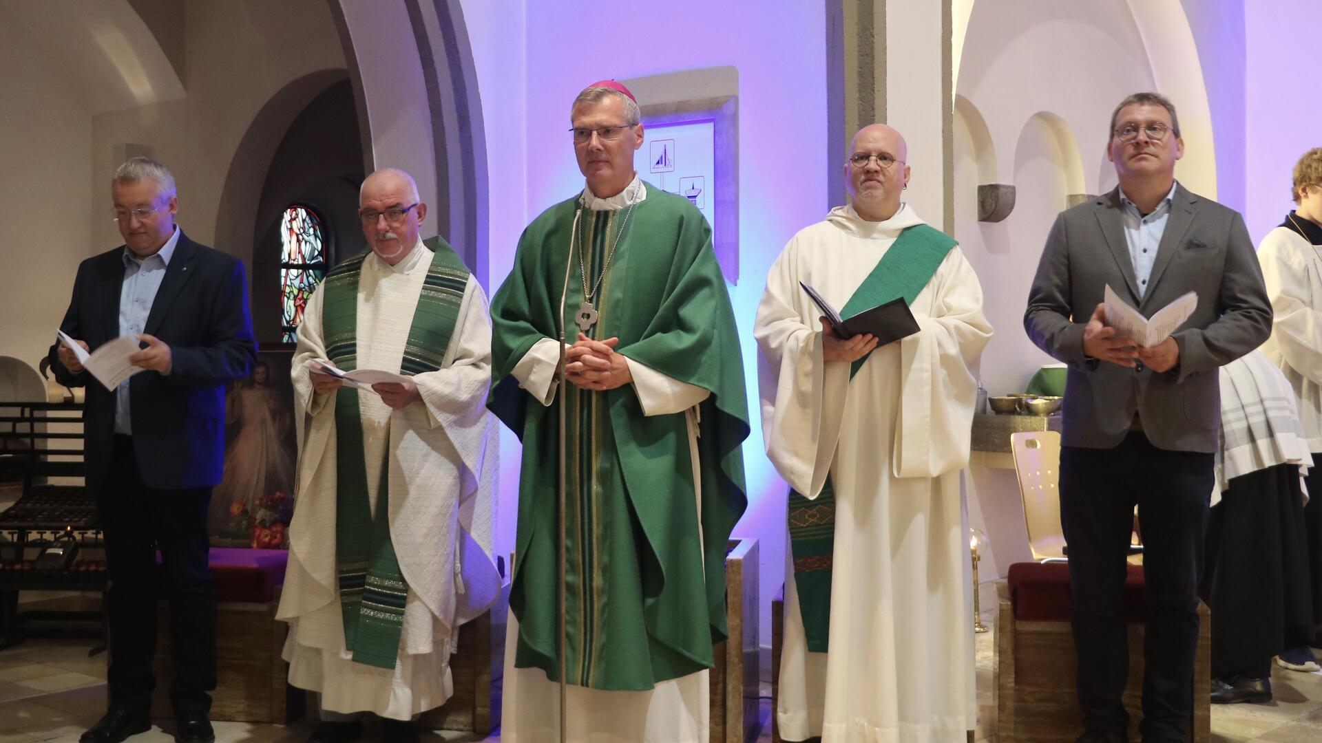 Fünf Männer, teilweise in Talaren. Sie sind im kirchlichen Kontext unterwegs.