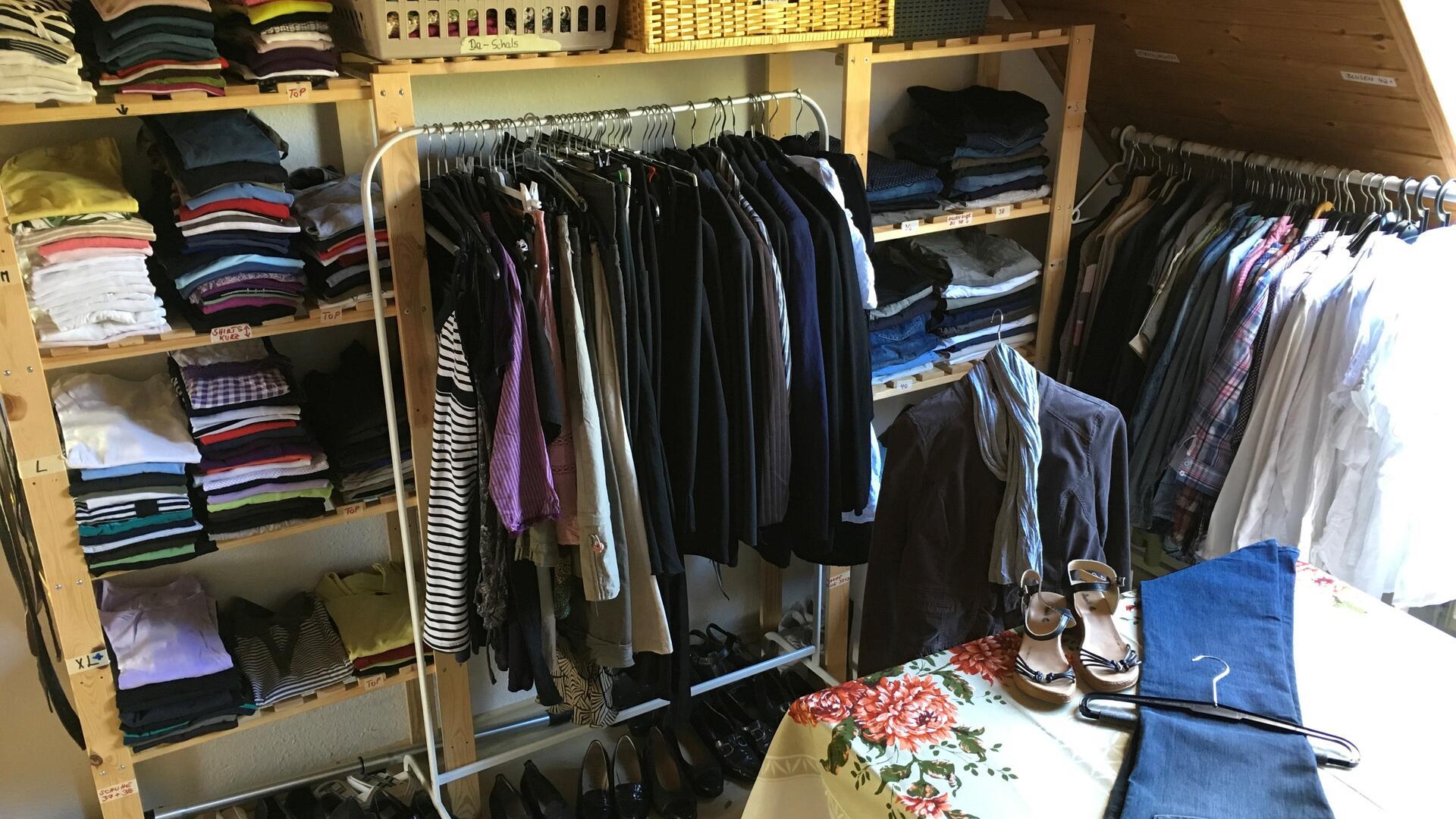 Dachgeschossraum mit Regalen und Stangen voller Kleidung