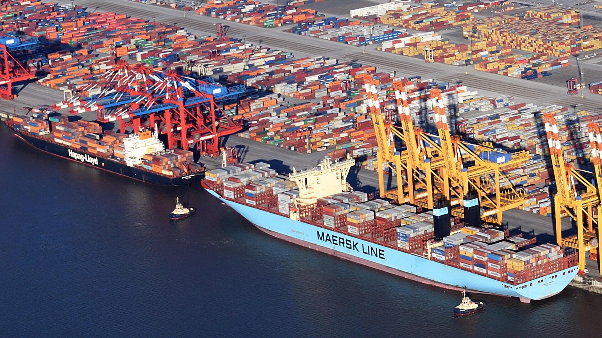 Luftaufnahme eines Containerterminals mit zwei großen Containerschiffen der Reedereien Hapag-Lloyd und Maersk, die an der Kaje liegen