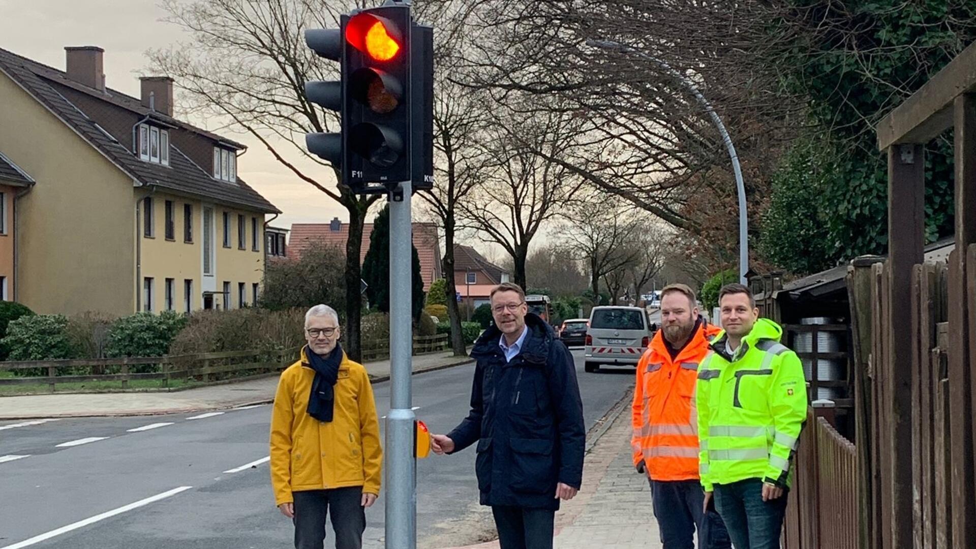 Vier Männer stehen vor einer roten Ampel. 