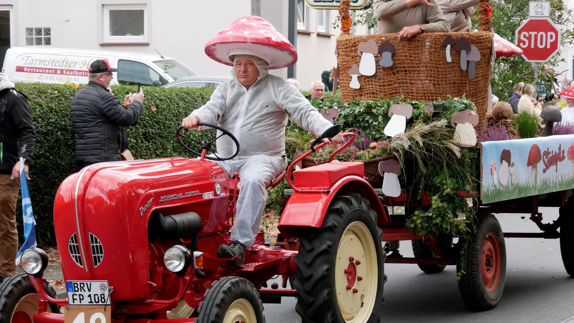 Eine Person fährt auf einem Traktor mit einem Festwagen dahinter.