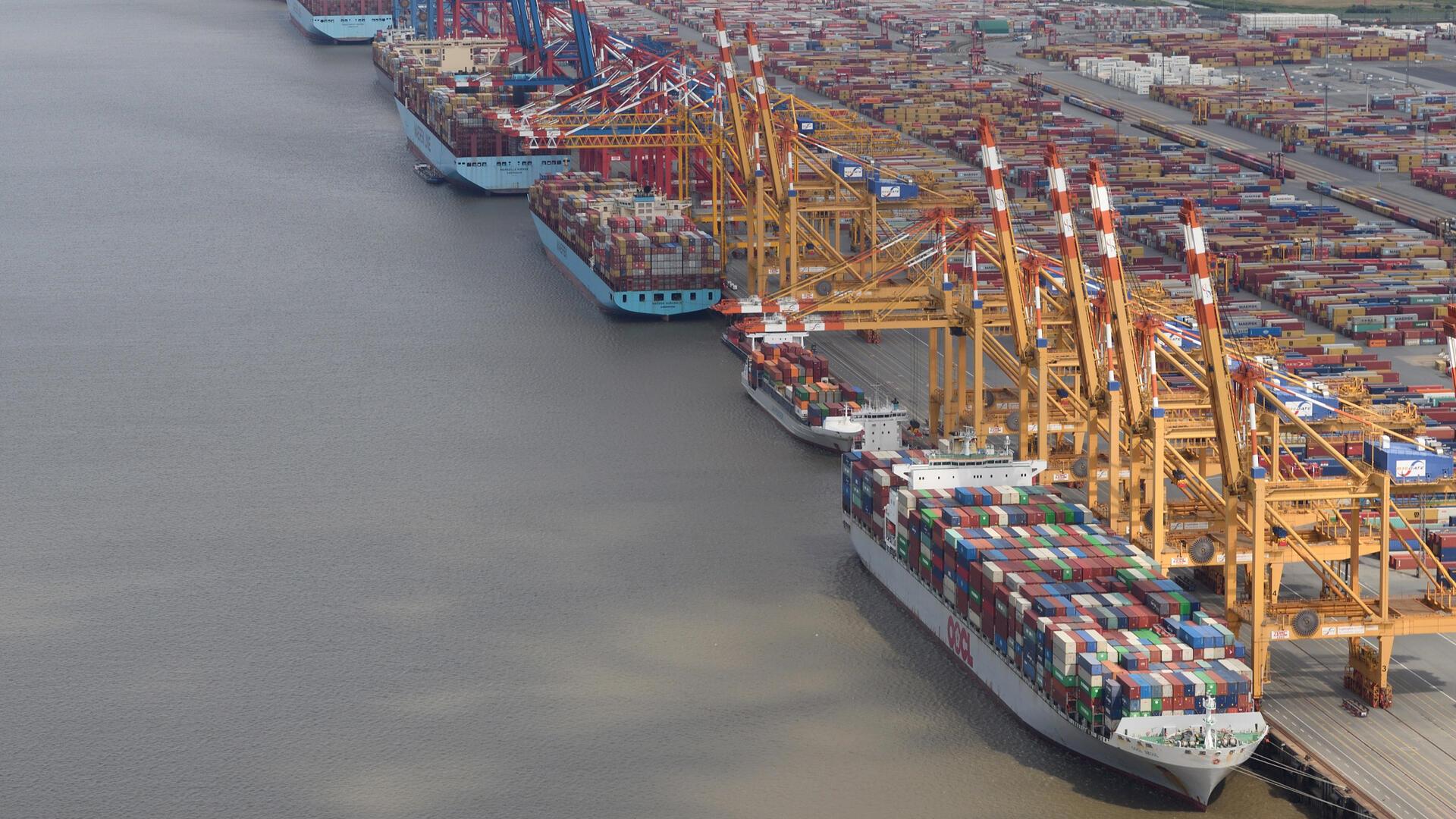 Luftaufnahme des Containerterminals in Bremerhaven mit mehreren Containerschiffen und gelben Verladekränen entlang der Kaje.